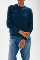 Model wearing Jumper1234 Navy cashmere crew neck jumper with red embroidered lifeguard detail