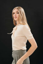 Female model wearing Jumper 1234 cream pointelle merino short sleeve jumper with a tie bow.