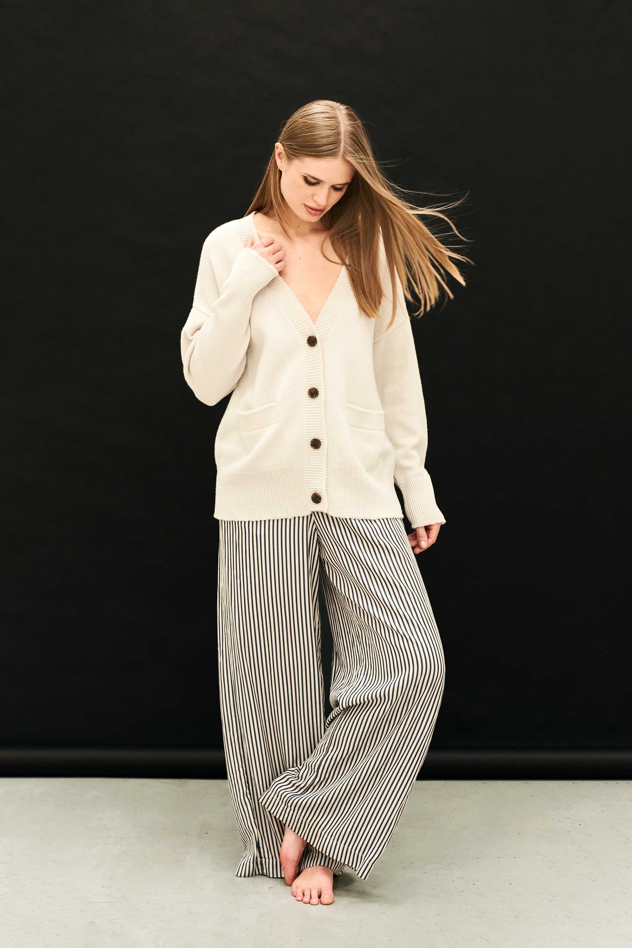 Female model wearing Jumper 1234 Heavier weight vee neck cardigan in stone. Oversize fit with distressed ribs.