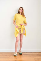 Blonde female model wearing Jumper 1234 Yellow cashmere vee neck cardigan with 'distressed' ribs tied around her waist.
