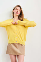 Blonde female model wearing Jumper 1234 Yellow cashmere vee neck cardigan with 'distressed' ribs