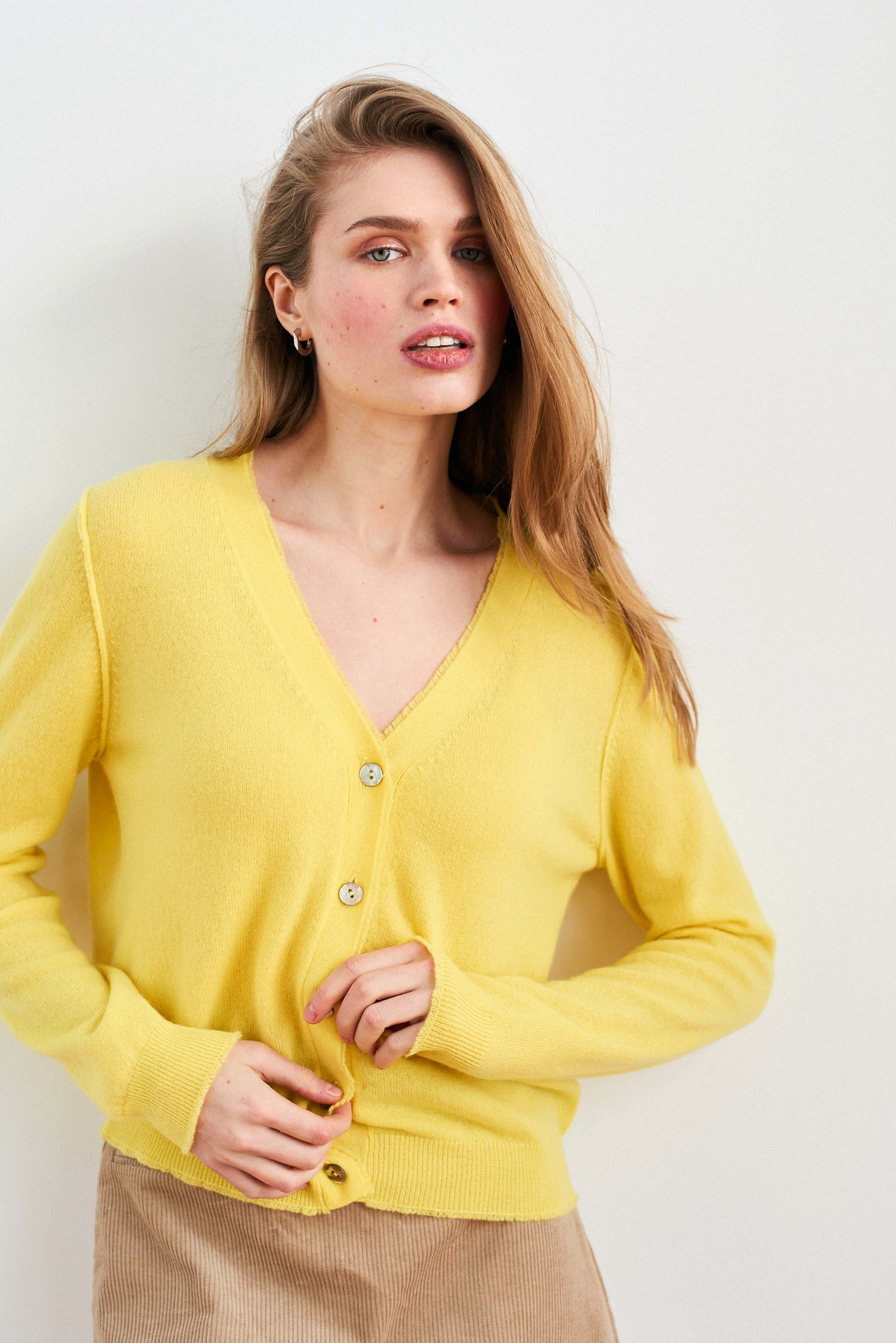 Blonde female model wearing Jumper 1234 Yellow cashmere vee neck cardigan with 'distressed' ribs