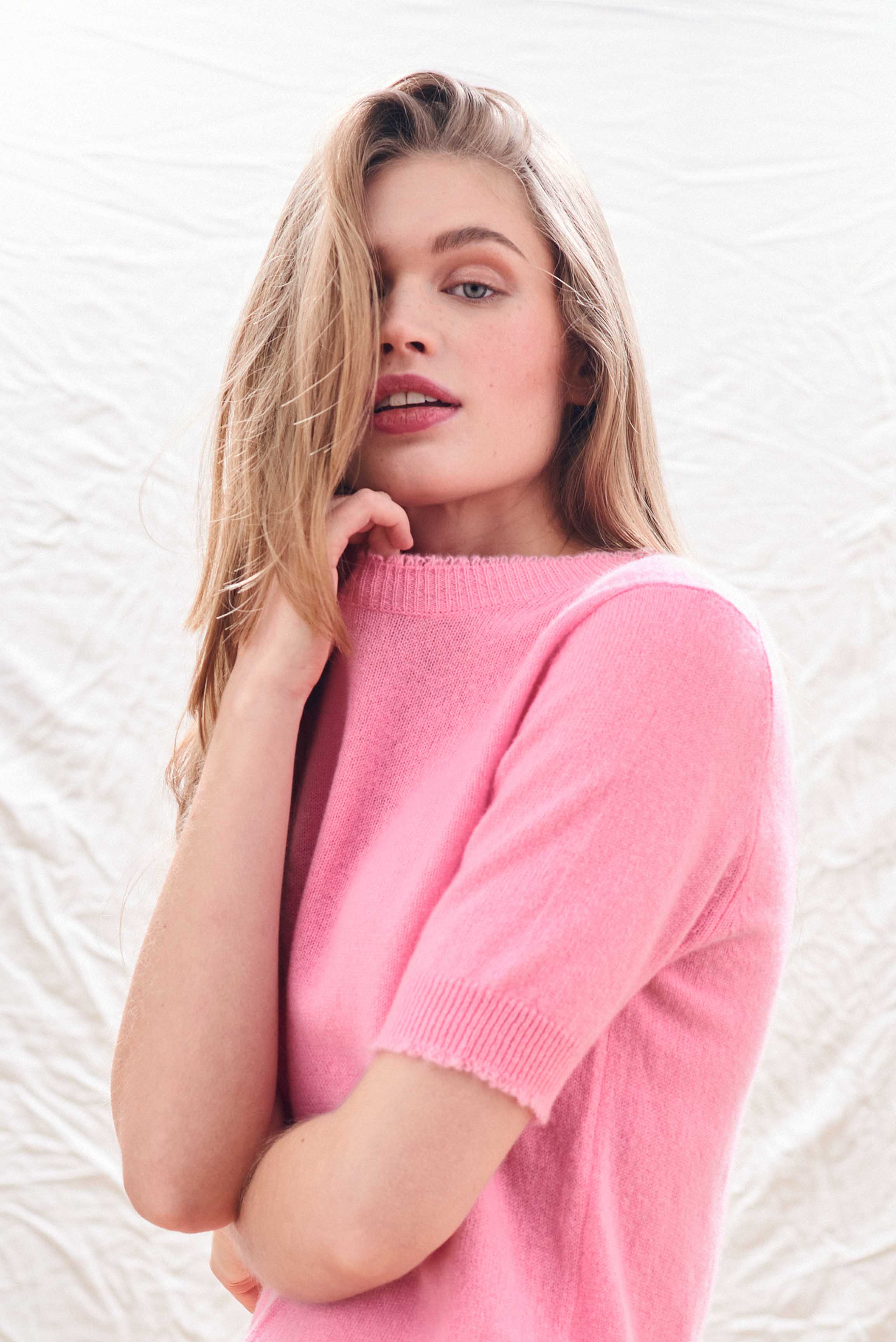 Female model wearing Jumper 1234 Candy pink short sleeve cashmere jumper with 'distressed' ribs.
